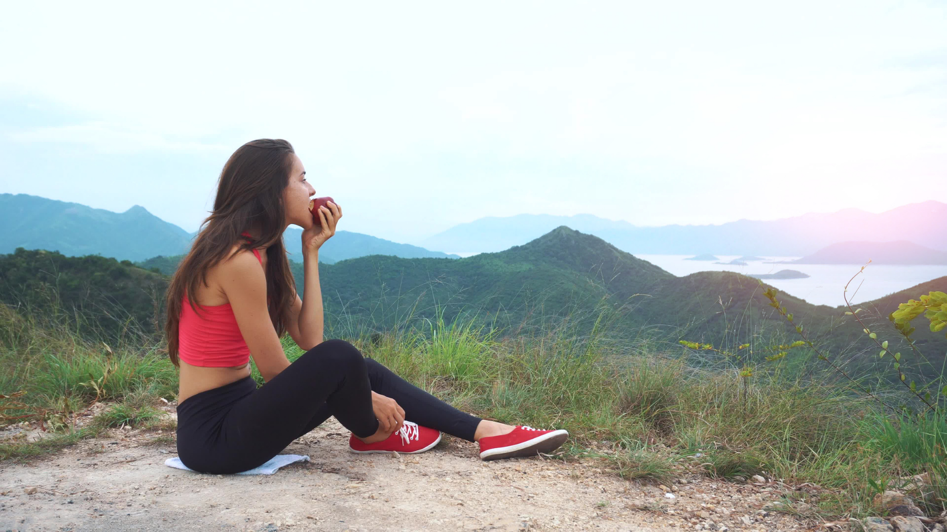 woman in running clothes eating apple outside